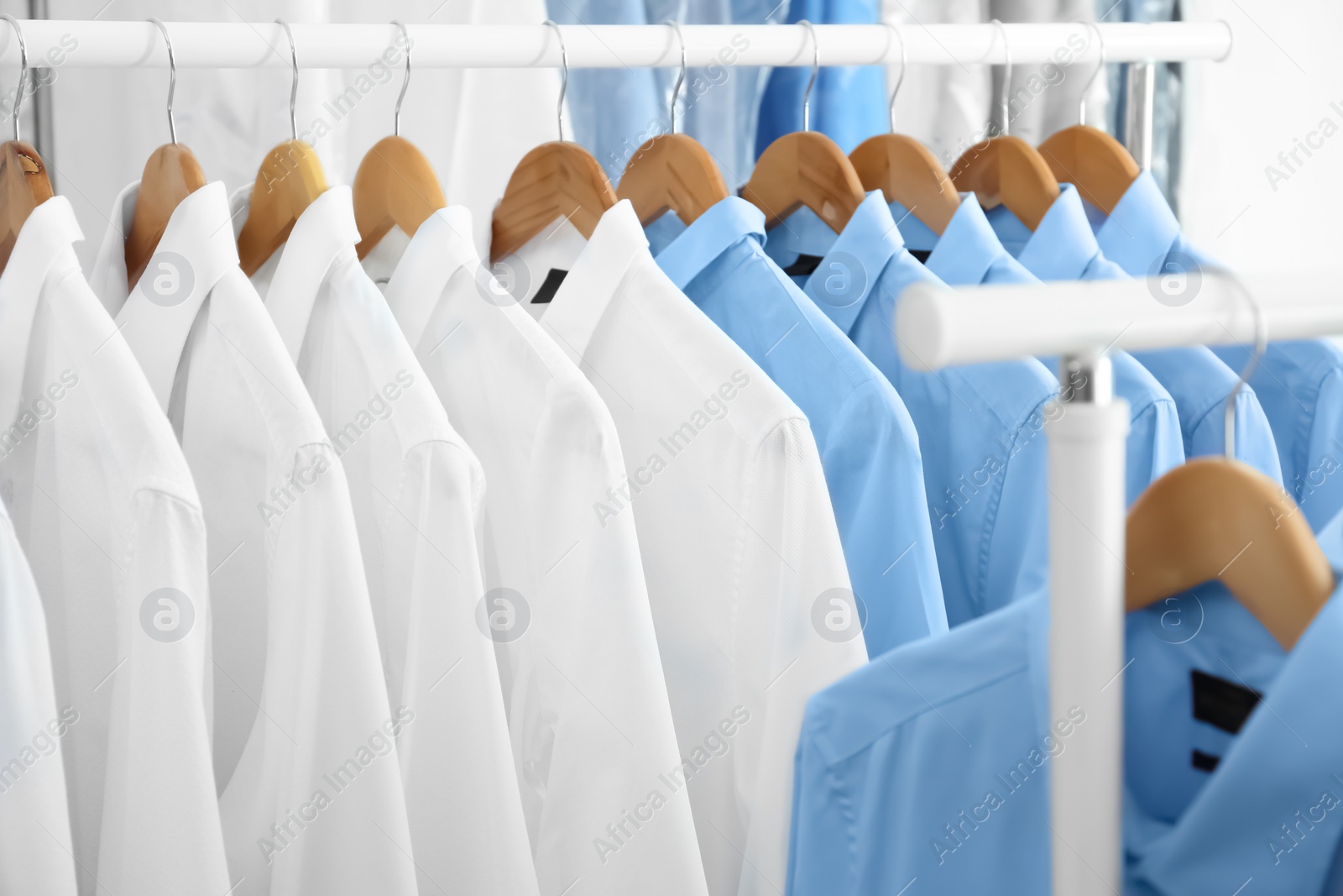 Photo of Rack with clean clothes on hangers after dry-cleaning indoors