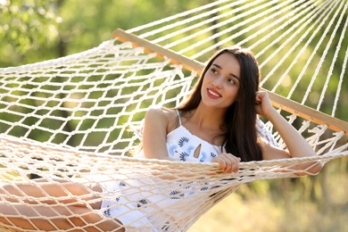 Photo of Young woman resting in comfortable hammock at green garden