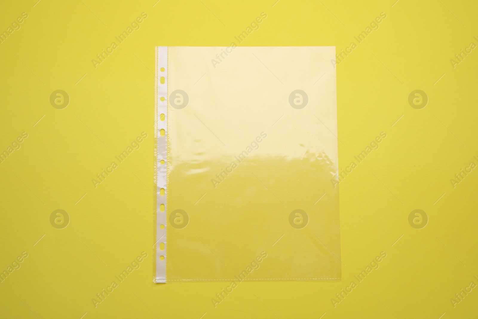 Photo of Empty punched pocket on yellow background, top view