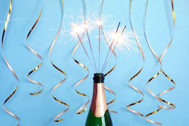 Photo of Creative composition with bottle of champagne and sparklers on color background