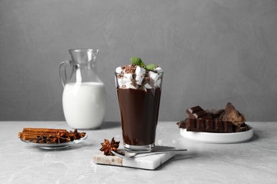 Glass of delicious hot chocolate with marshmallows and fresh mint on light grey marble table