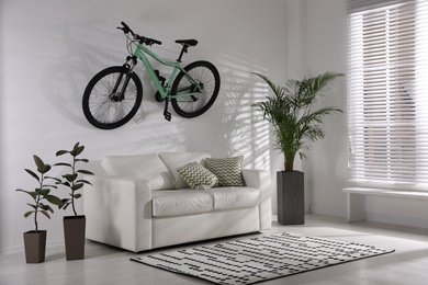 Photo of Stylish living room interior with white sofa and green bicycle