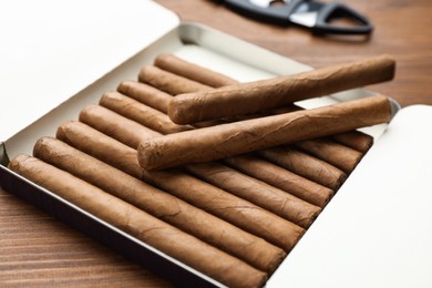 Photo of Humidor with cigars on wooden table, closeup