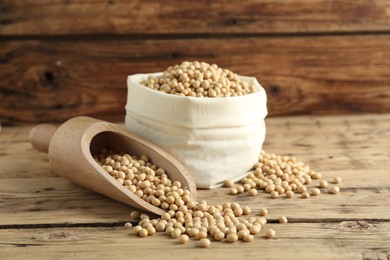 Photo of Scoop and sack with soy on wooden table