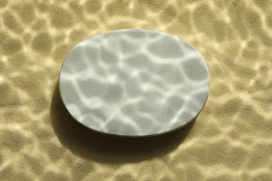 Photo of Stylish presentation for product. Stone podium on sand, top view