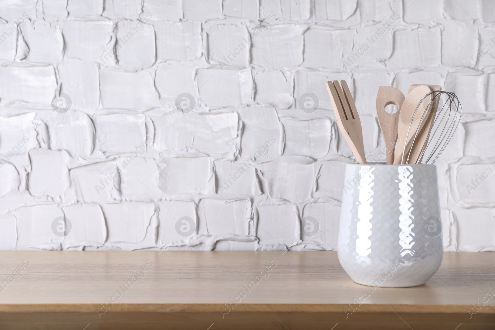 Photo of Holder with different kitchen utensils on wooden table. Space for text