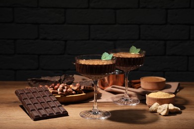 Photo of Dessert bowls of delicious hot chocolate and ingredients on wooden table