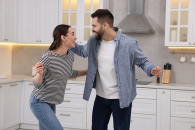 Happy lovely couple dancing together in kitchen