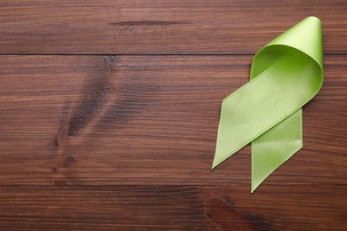 Photo of World Mental Health Day. Green ribbon on wooden background, top view with space for text