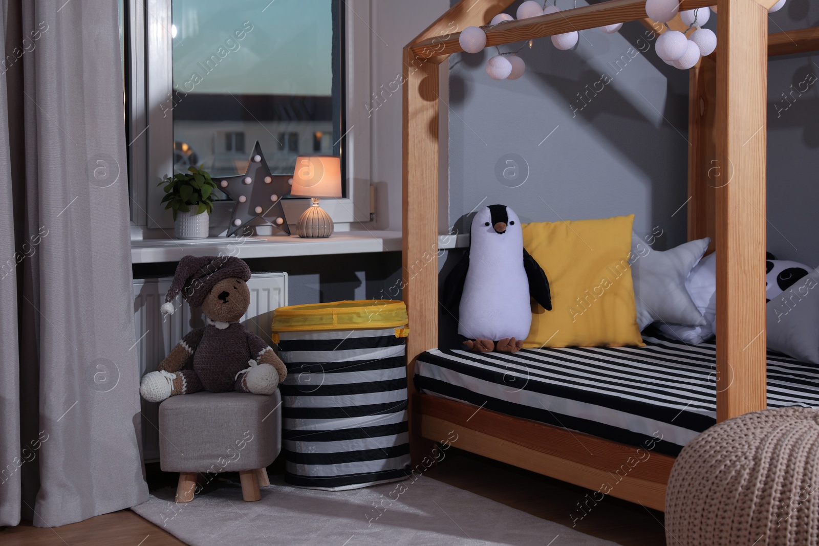 Photo of Stylish child room interior with comfortable house bed and toys