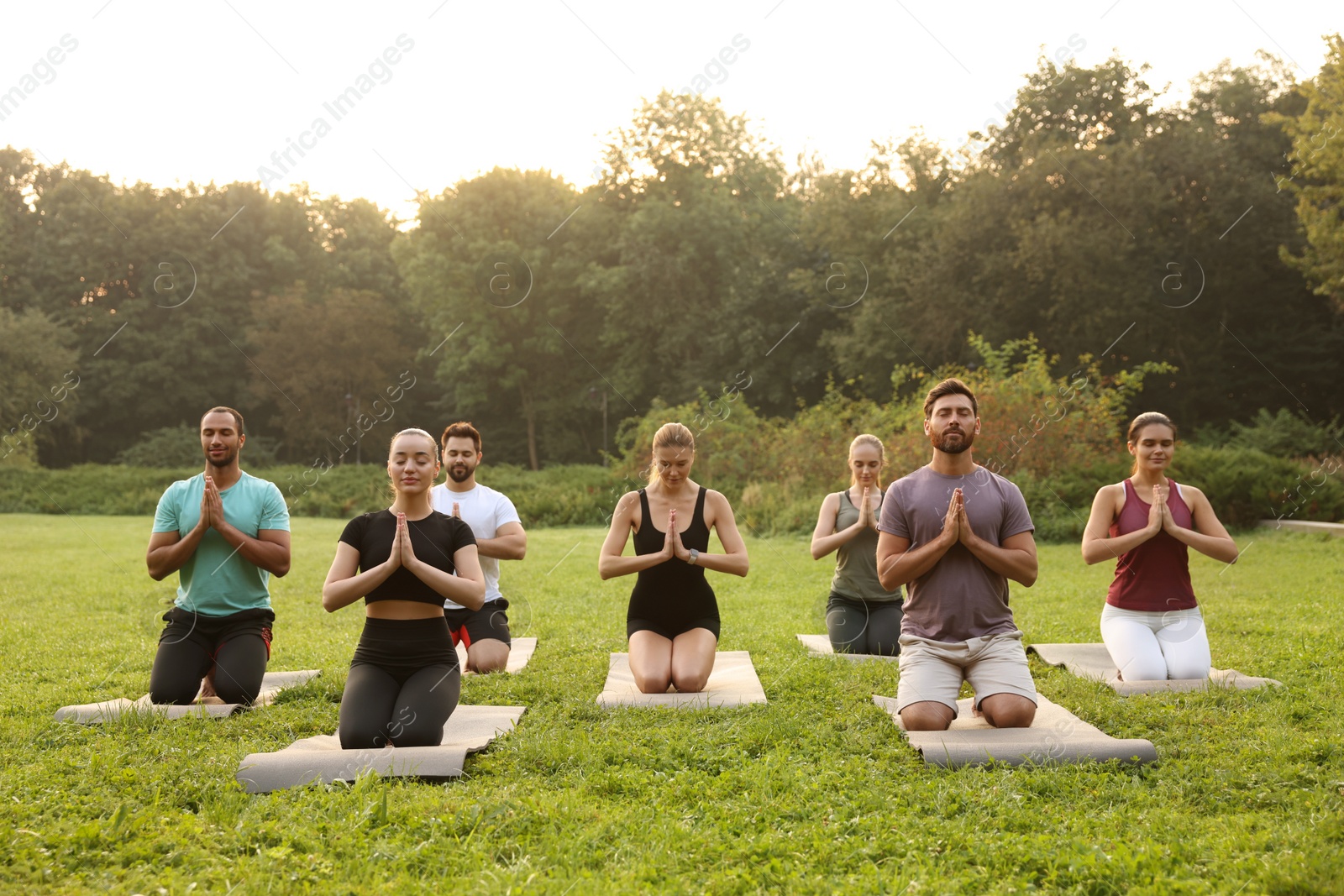 Photo of Group of people practicing yoga on mats outdoors