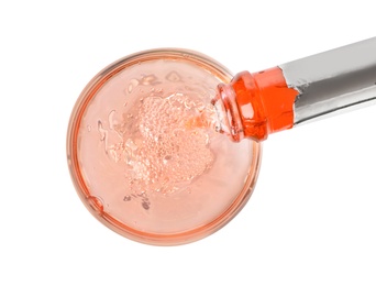 Photo of Rose champagne pouring from bottle into glass isolated on white, top view