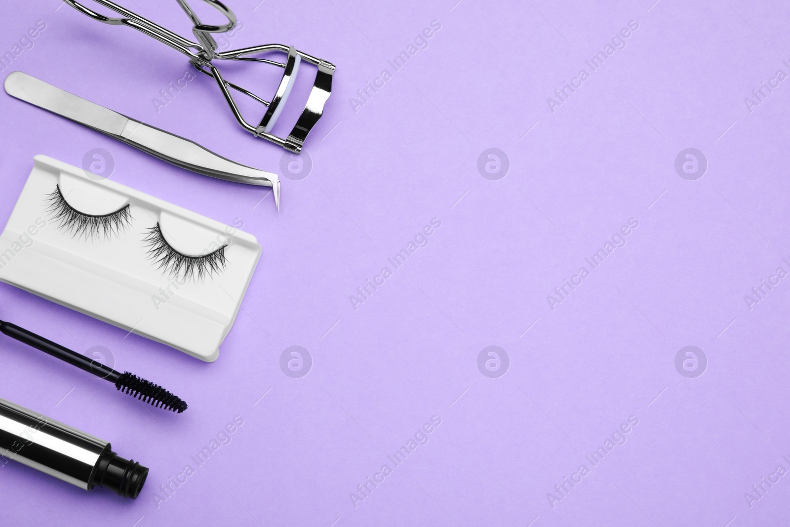Photo of Flat lay composition with fake eyelashes, mascara brush and tools on lilac background. Space for text