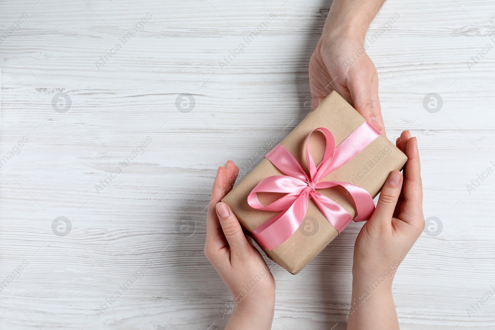 Photo of Man giving gift box to woman on white wooden table, top view. Space for text