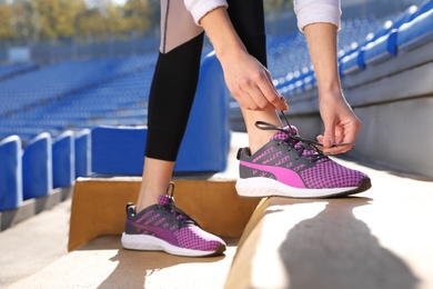 Photo of Sporty woman tying shoelaces before running at stadium