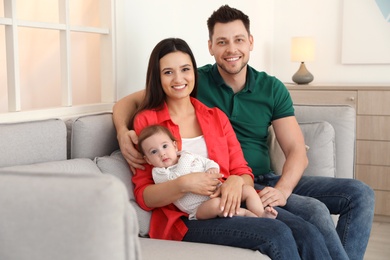 Happy couple with adorable baby on sofa at home. Family time