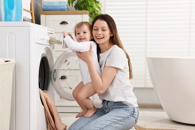 Photo of Happy mother with her daughter washing baby clothes in bathroom