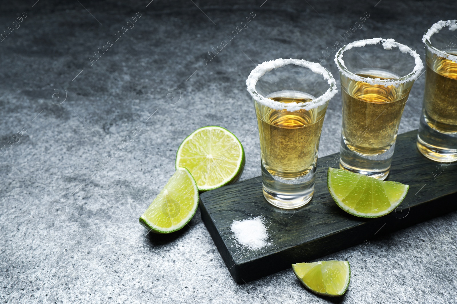 Photo of Mexican Tequila shots, lime slices and salt on grey table