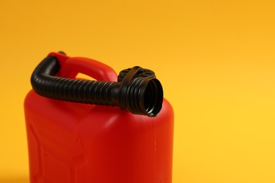 Red plastic canister with tube on orange background, closeup. Space for text