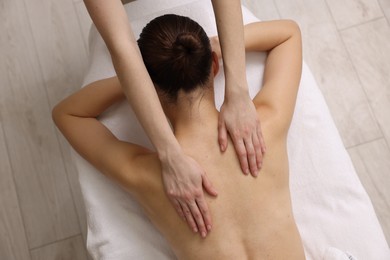 Woman receiving back massage on couch in spa salon, top view