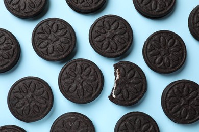 Photo of Tasty sweet sandwich cookies on light blue background, flat lay