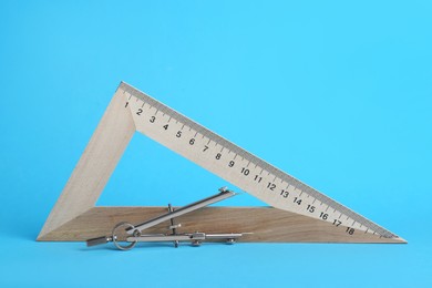 Triangle ruler and compass on light blue background