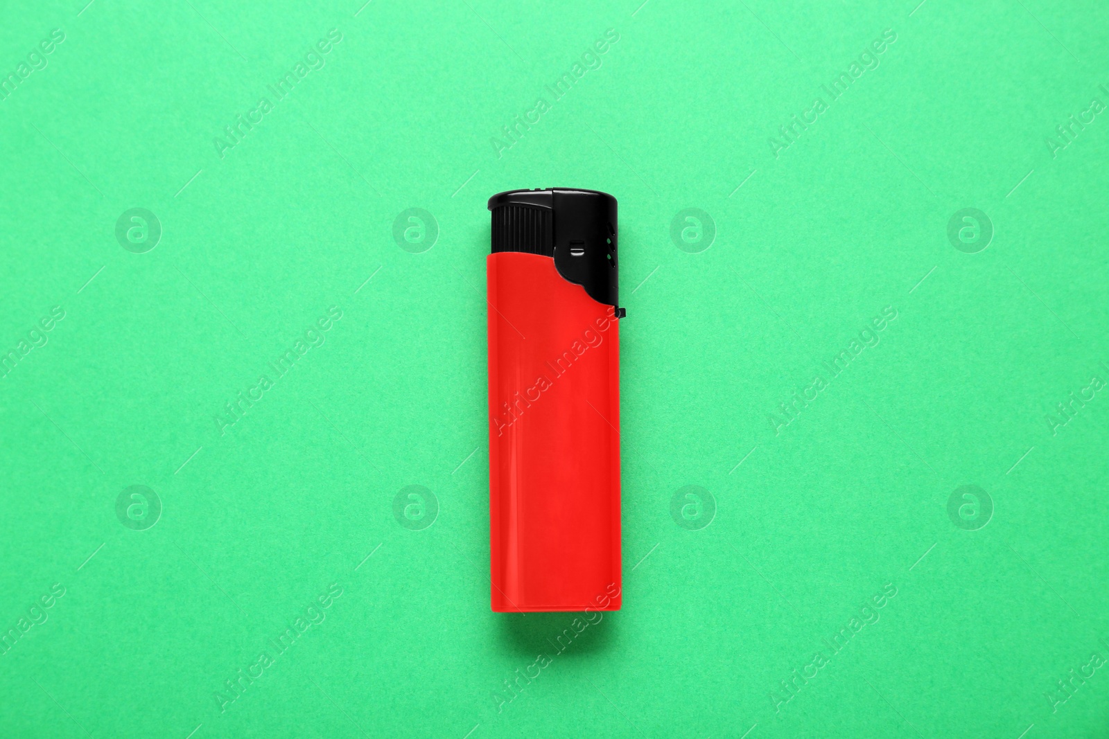 Photo of Stylish small pocket lighter on green background, top view