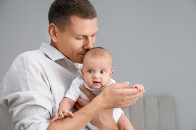 Photo of Happy father holding his cute baby at home, space for text