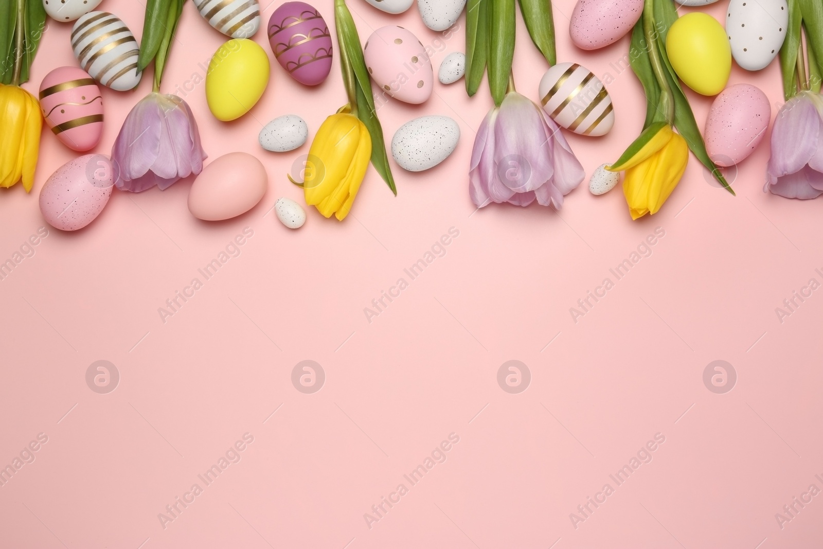 Photo of Flat lay composition with festively decorated Easter eggs and beautiful tulips on pink background. Space for text