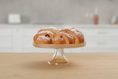 Photo of Stand with delicious croissants on wooden table in kitchen