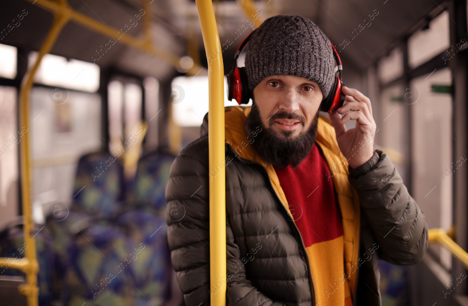 Photo of Mature man with headphones listening to music in public transport