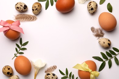 Photo of Frame of Easter eggs, twigs and flowers on white background. Space for text