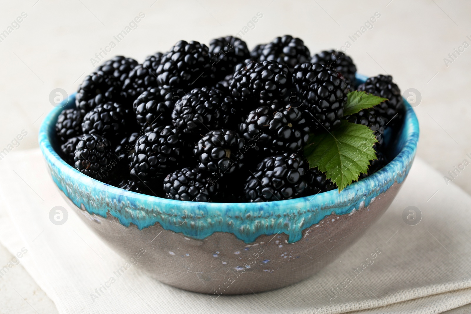 Photo of Tasty ripe blackberries in bowl on table