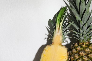 Photo of Whole and cut ripe pineapples on white background, closeup. Space for text