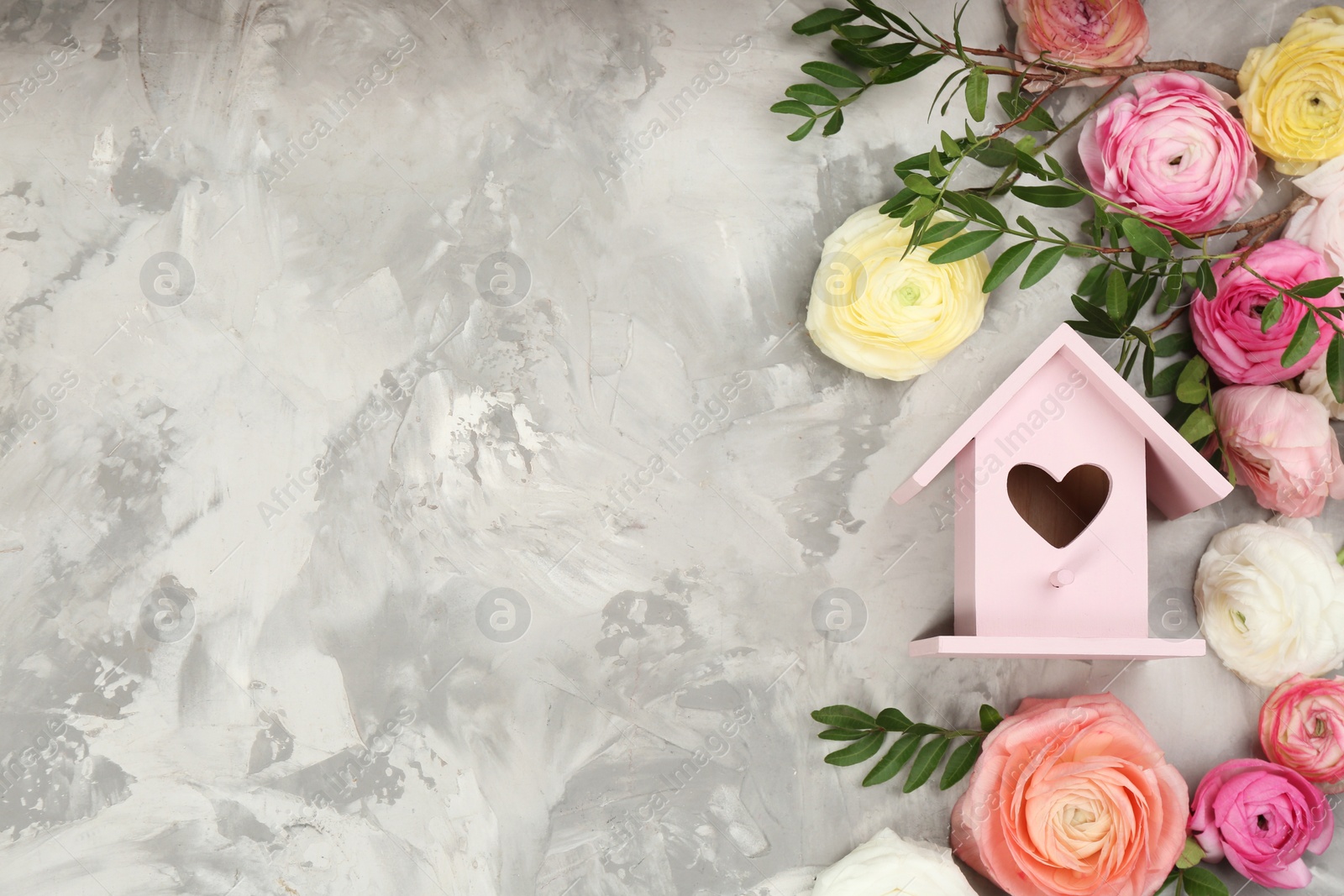 Photo of Stylish bird house and fresh eustomas on light grey stone background, flat lay. Space for text