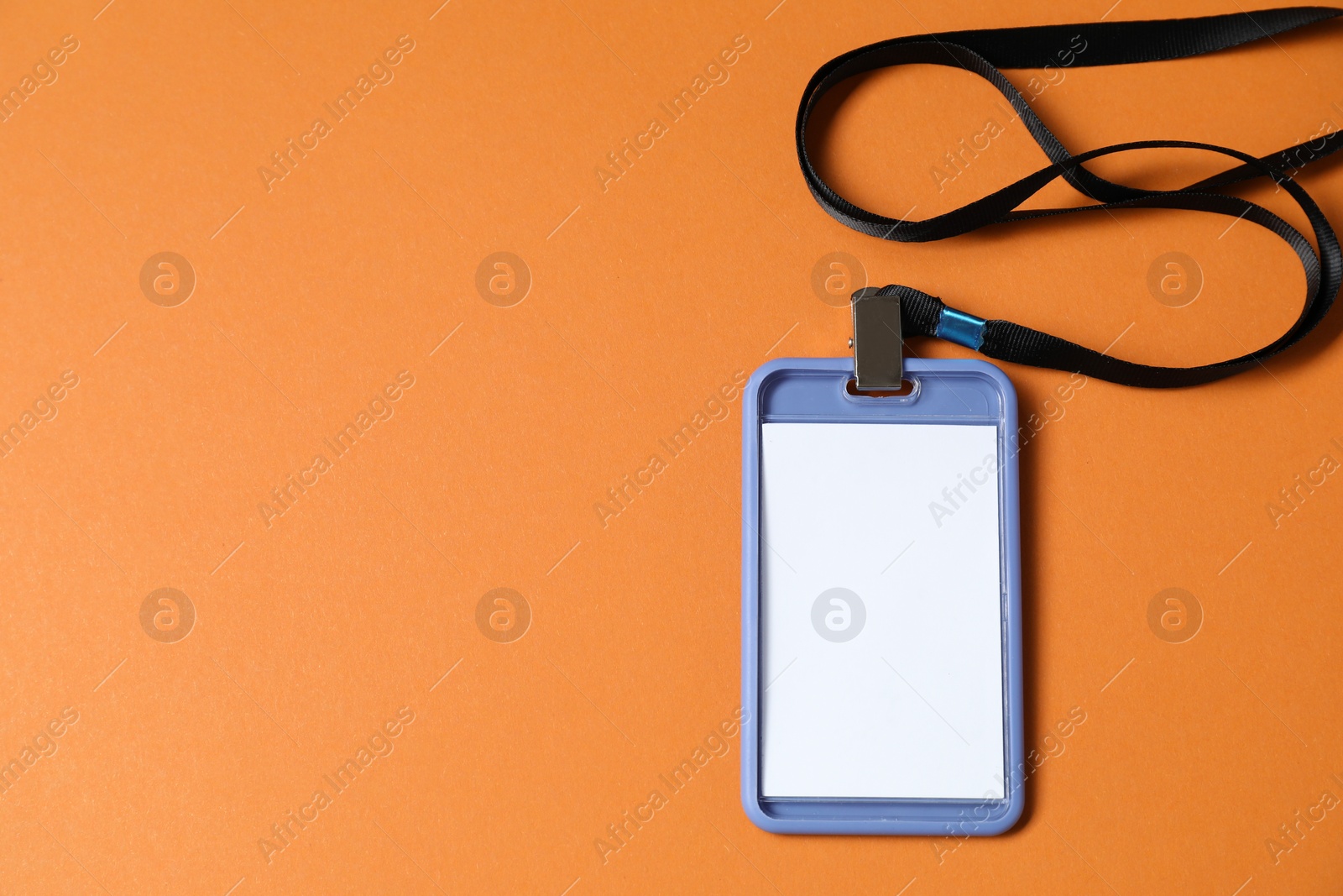 Photo of Blank badge with string on orange background, top view. Space for text