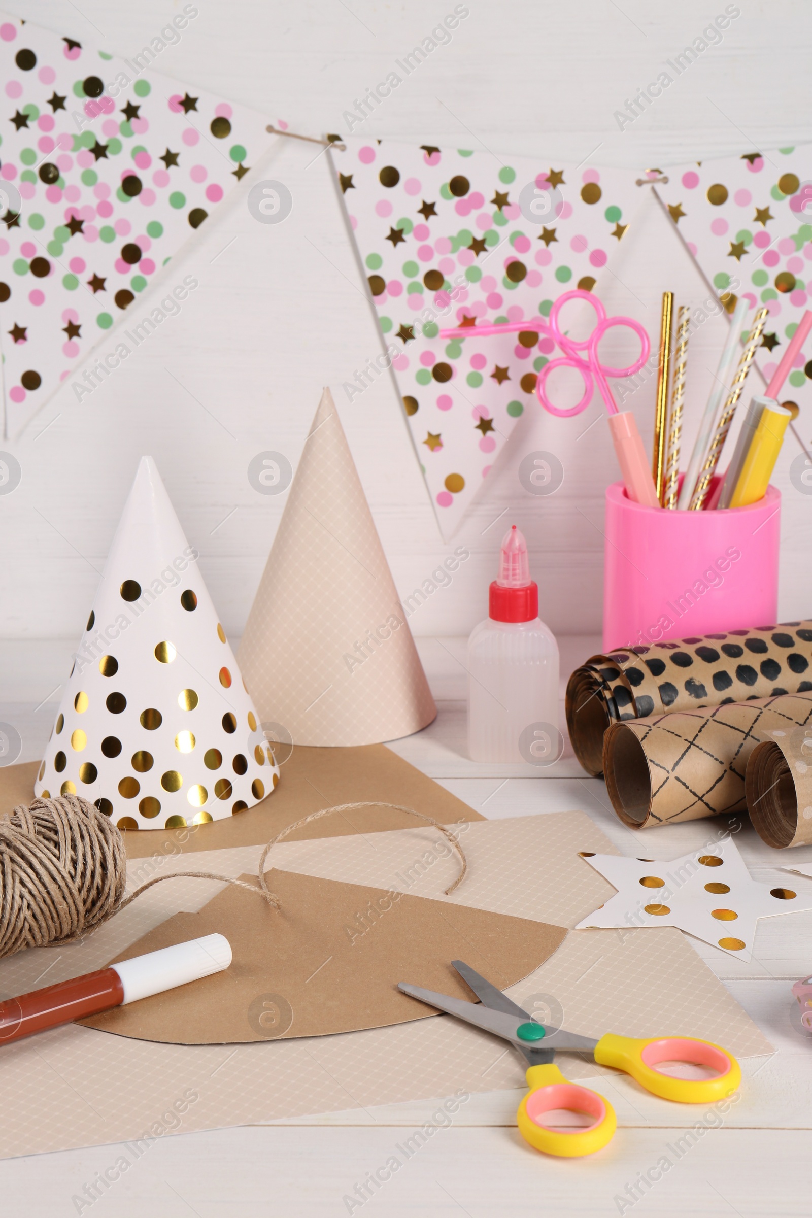 Photo of Stationery and different materials to create party hats on white wooden table. Handmade decoration