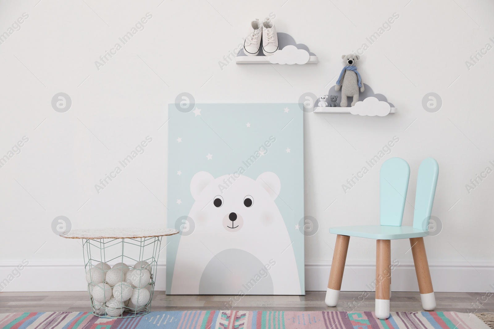 Photo of Poster with bear, chair and basket near light wall in baby room. Interior design