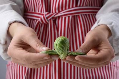 Photo of Woman separating leaves from fresh brussel sprout, closeup