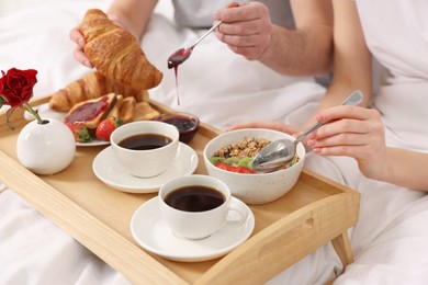 Photo of Couple eating tasty breakfast in bed, closeup