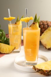 Tasty pineapple cocktail and sliced fruit on white table