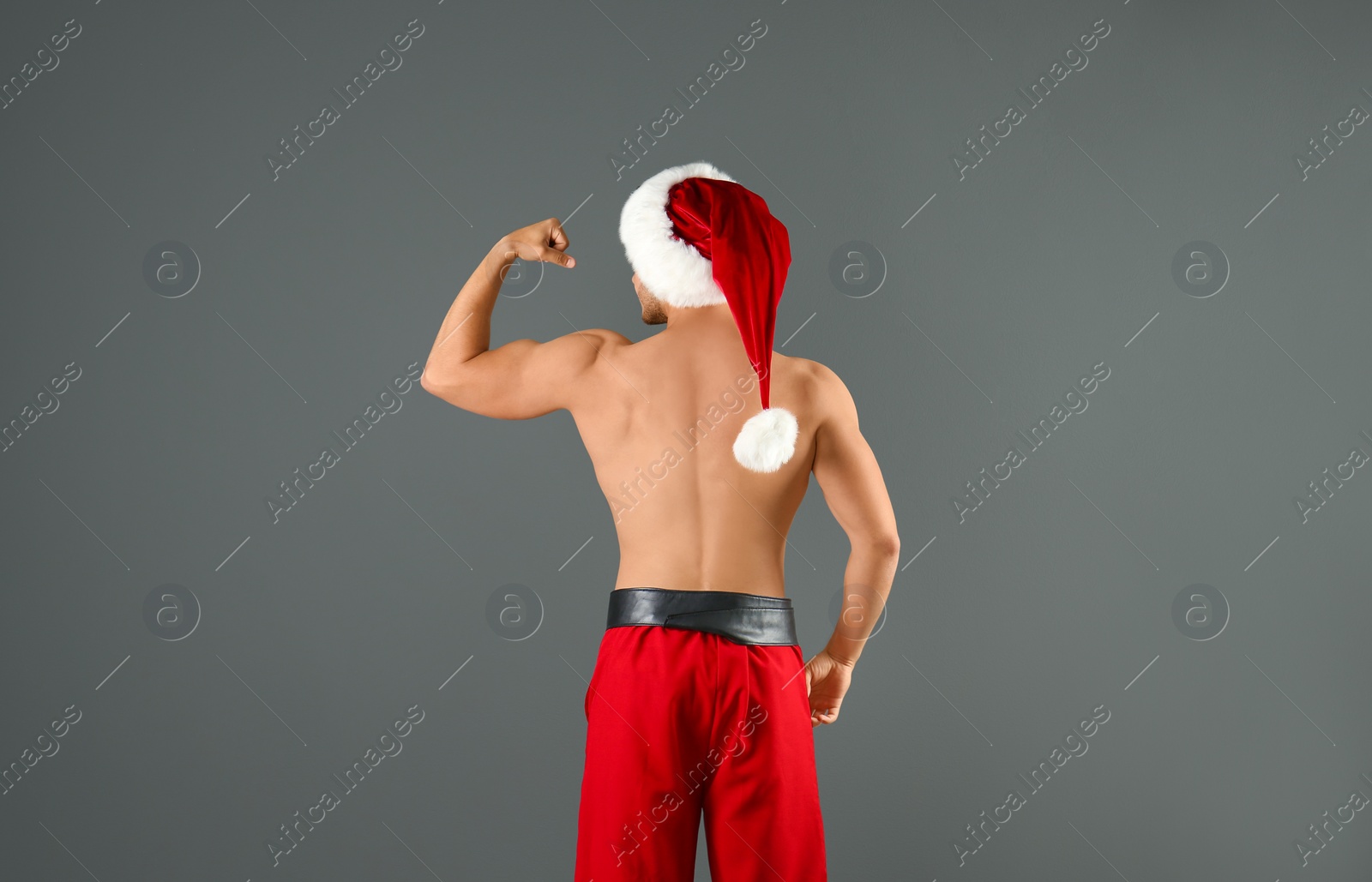 Photo of Shirtless young Santa Claus with sexy body on color background