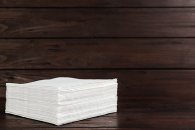 Photo of Clean napkins on wooden table, space for text