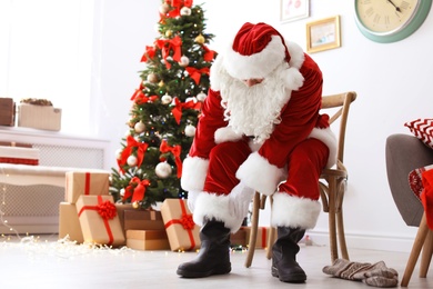 Photo of Authentic Santa Claus putting on traditional costume indoors