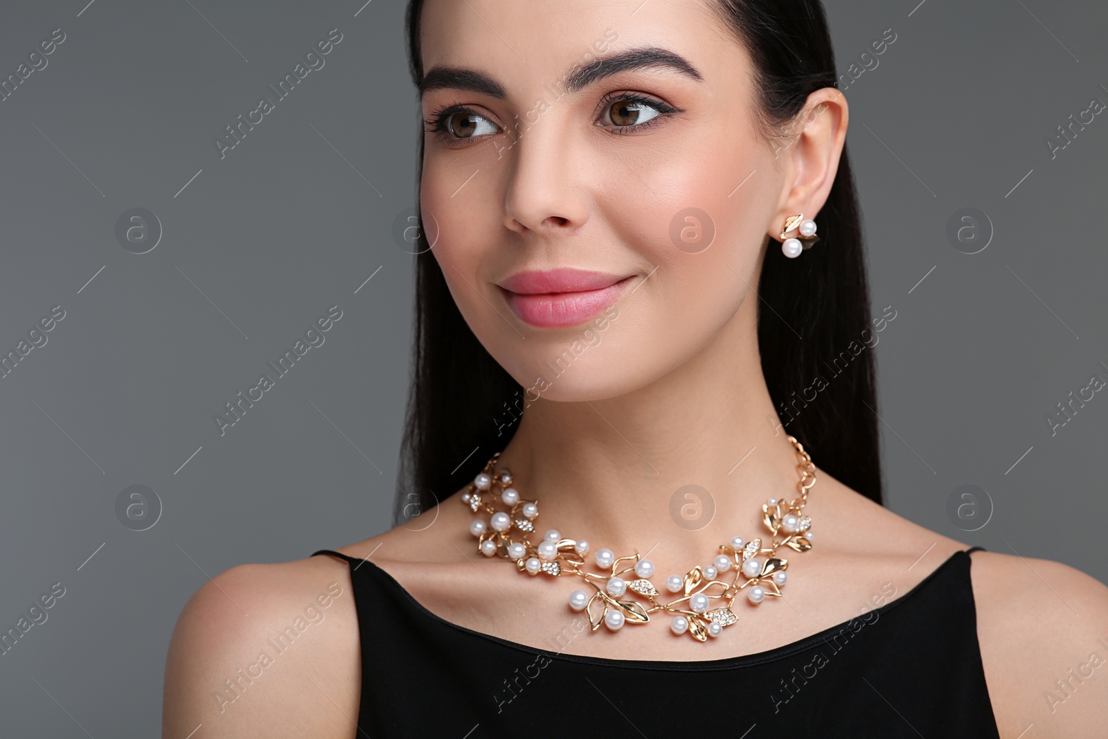 Photo of Beautiful young woman with elegant jewelry on dark grey background