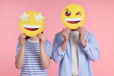 Photo of People covering faces with emoticons on pink background