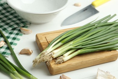 Photo of Fresh green spring onions and garlic cloves on white wooden table