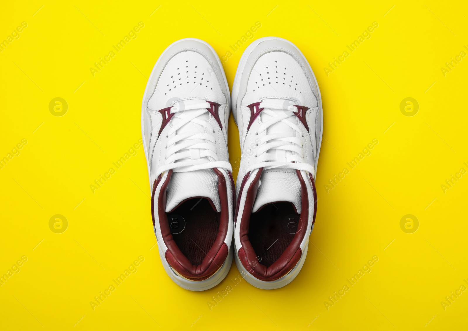 Photo of Pair of stylish shoes on yellow background, top view