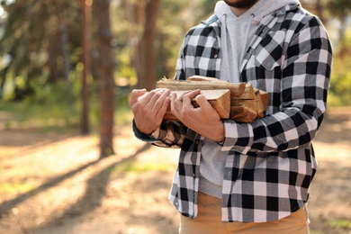 Photo of Man with cut firewood in forest, closeup