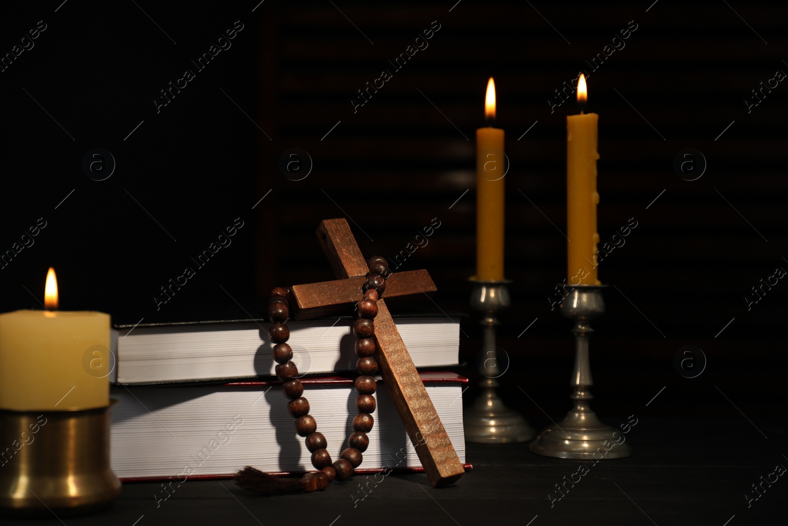 Photo of Church candles, Bible, rosary beads and cross on wooden table